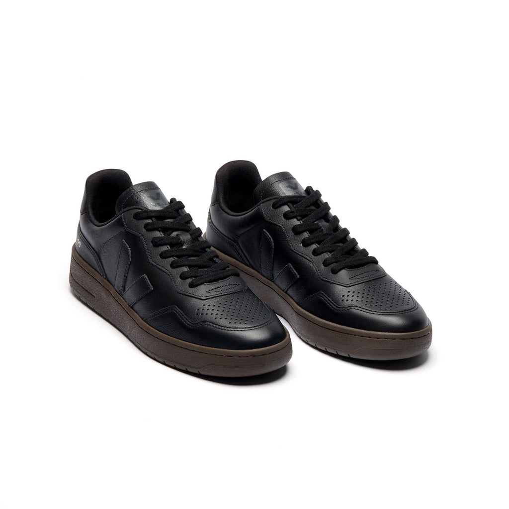 Three-quarter view of eco-friendly VEJA V-90 O.T. Leather unisex sneakers with black leather and eagle accents